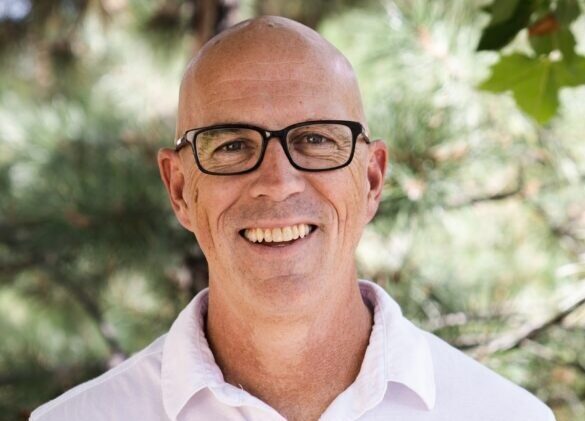 An interview with David Coyne, REALTOR® at Legacy Real Estate Network powered by Place, Inc., Keller Williams Northern Arizona. David serves as the Co-Chairperson of the Culture Committee on the Keller Williams Northern Arizona Agent Leadership Council (ALC) for 2022. David is wearing a white shirt, glasses, and is facing forward, smiling broadly.